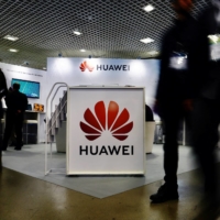 Visitors walk past the Huawei logo at the World Artificial Intelligence Cannes Festival in Cannes, France, on Feb.10. | REUTERS