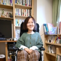 Yuda uses her electric wheelchair during the daytime. Her bookshelves are filled with books on sociology. | NISHINIPPON SHIMBUN