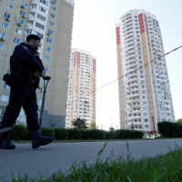 Russian law enforcement officers stand guard near a damaged multistory Moscow apartment block on Tuesday following a reported drone attack. | REUTERS