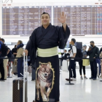 Ozeki Kirishima waves before boarding a flight to Mongolia on Monday. | KYODO