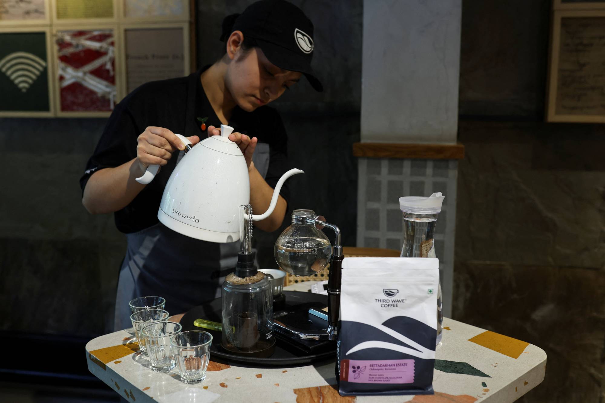 An employee shows brewing coffee with a Syphon coffee maker at a Third Wave Coffee outlet in New Delhi on May 30. | REUTERS