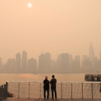 People watch the sunset as haze and smoke caused by wildfires in Canada hang over the Manhattan skyline, in New York on Wednesday.
 | REUTERS