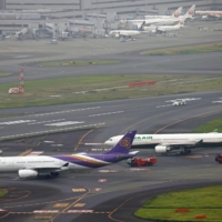 Passenger planes operated by Thai Airways and Taiwan\'s Eva Airways sit on a taxiway after making contact at Tokyo\'s Haneda Airport on Saturday. | KYODO