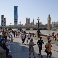 Visitors walk alongside the River Thames, against a backdrop of the Palace of Westminster, in London on Saturday. | BLOOMBERG