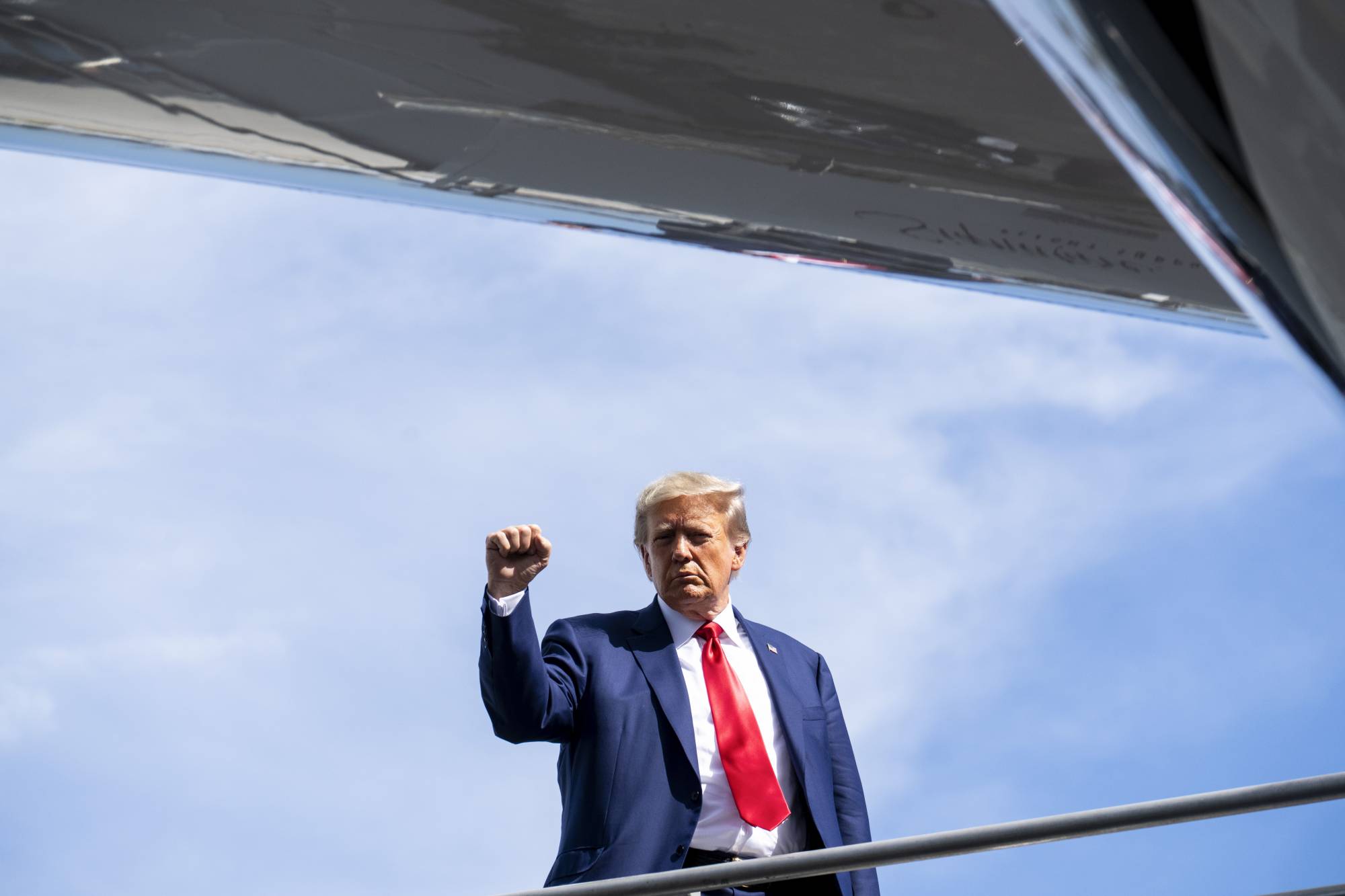 Former U.S. President Donald Trump gestures as he boards his plane in Miami on Tuesday. | DOUG MILLS / THE NEW YORK TIMES