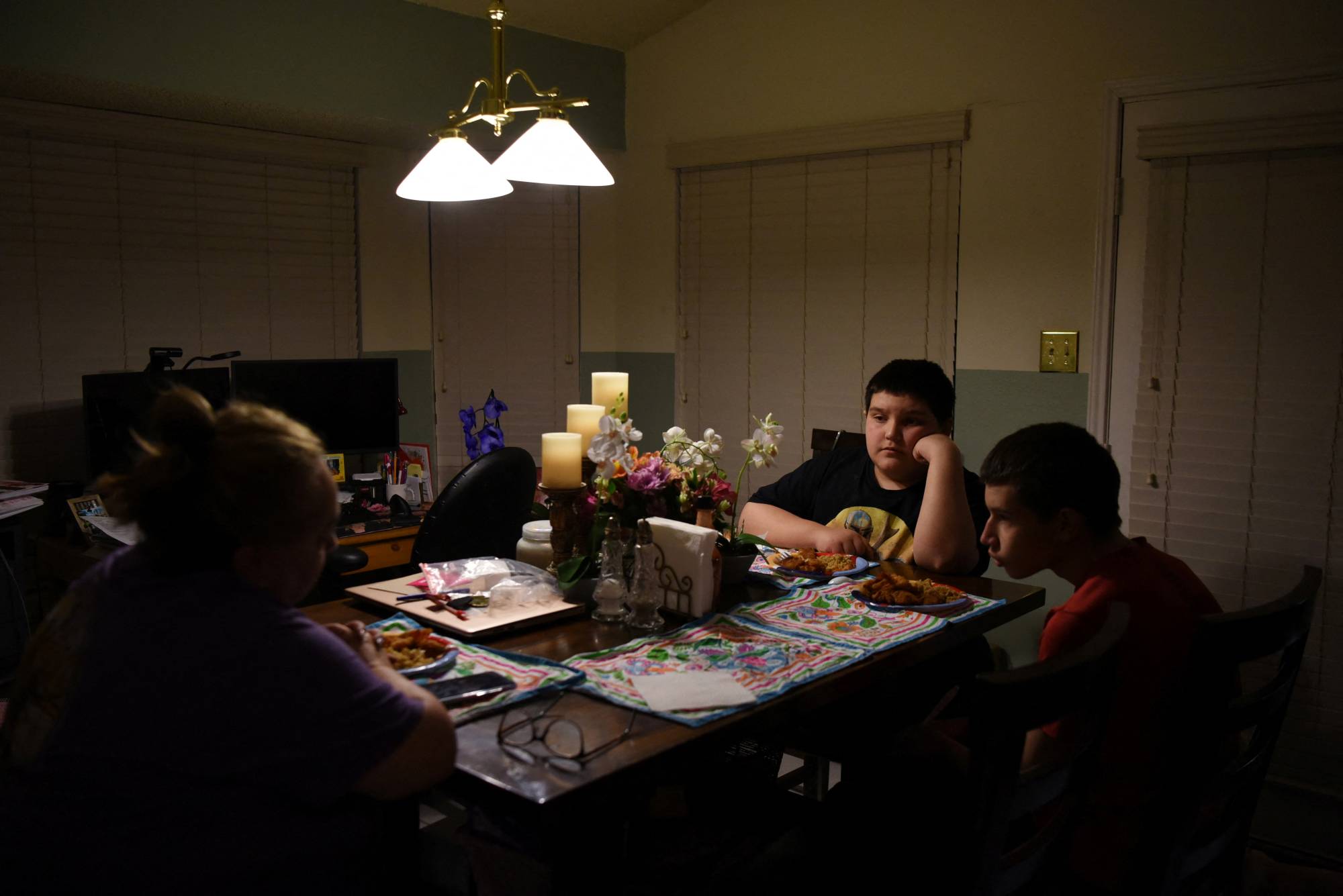 A family sits down for dinner without the father, who died from COVID-19 in December 2020 in Converse, Texas, in February 2022. | REUTERS