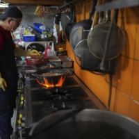 Lee Hae-yeon cooking at his restaurant in Seoul. Leftover food is collected in a bucket all day.  | CHANG W. LEE / THE NEW YORK TIMES