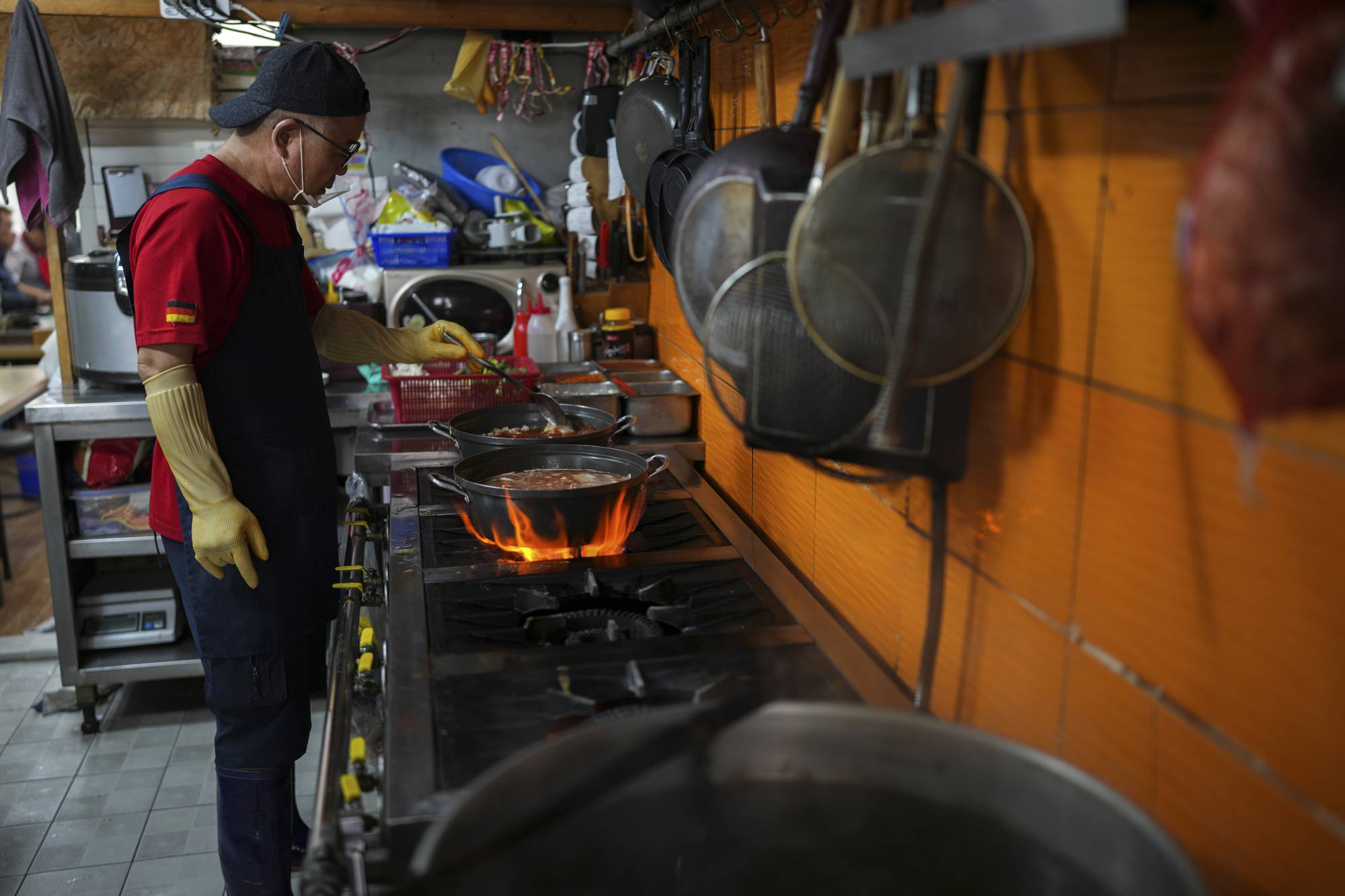 Lee Hae-yeon cooking at his restaurant in Seoul. Leftover food is collected in a bucket all day. | Chang W. Lee / The New York Times