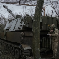 A Ukrainian soldier receives coordinates for a Russian position in preparation to fire an American-made M109 self-propelled howitzer, on the outskirts of Bakhmut, Ukraine, in April. | MAURICIO LIMA / THE NEW YORK TIMES