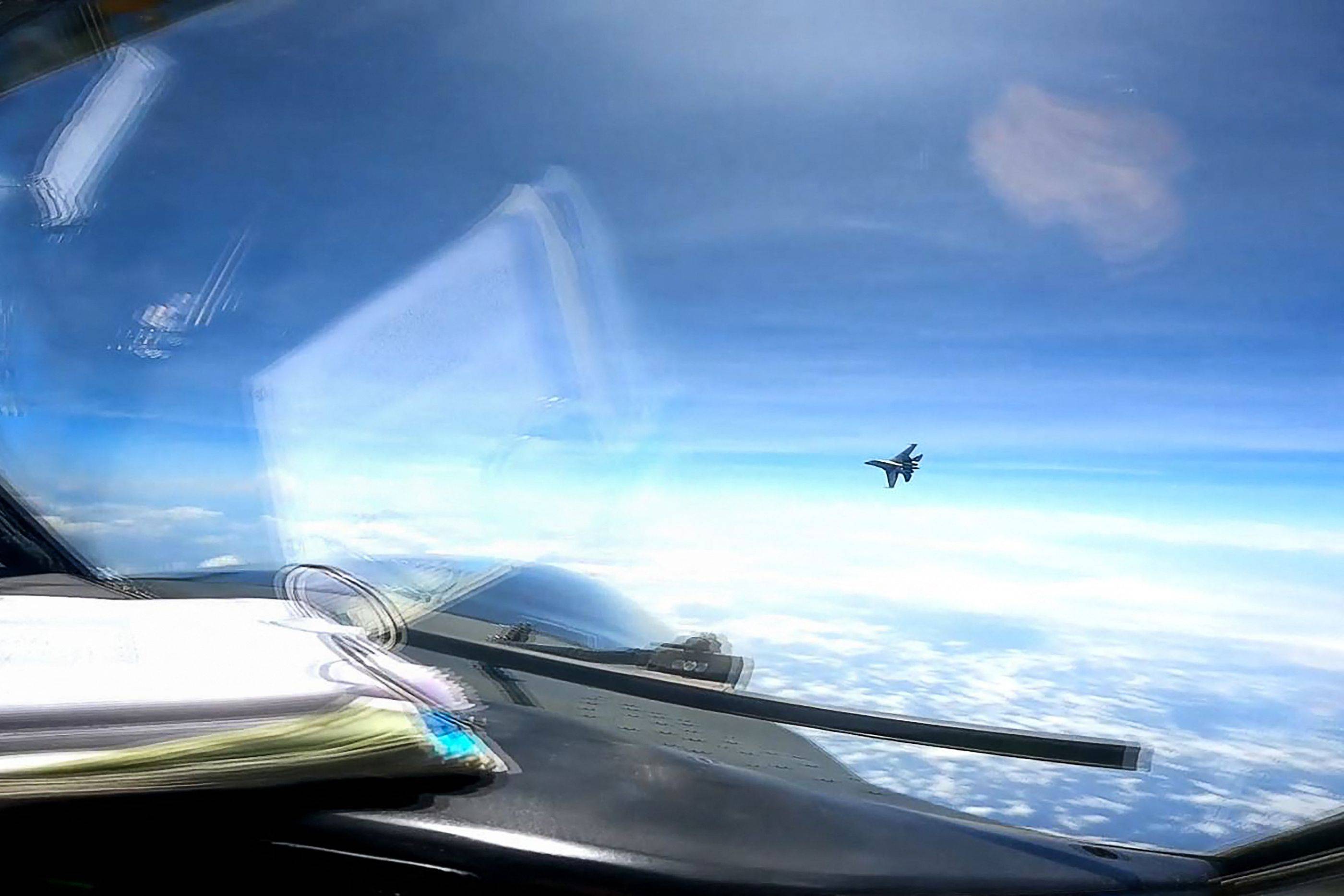 A Chinese military J-16 fighter jet flies in front of the nose of a U.S. Air Force RC-135 reconnaissance aircraft in international airspace over the South China Sea on May 26. | DVIDS / VIA AFP-JIJI