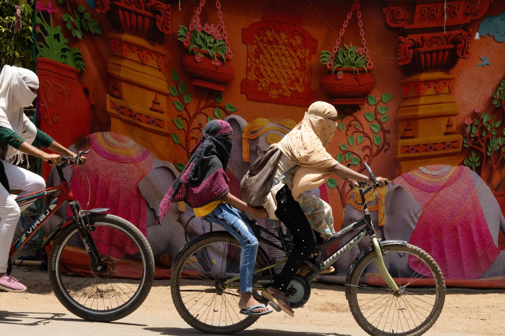 Cyclists cover their faces with cloth to protect from the sun in Bilaspur, Chhattisgarh, India, in May. | BLOOMBERG