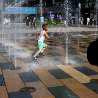 Children cool off in a water fountain amid a heat wave, at a shopping area in Beijing on Thursday. | REUTERS