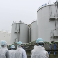 Members of an International Atomic Energy Agency investigation team inspect tanks containing treated radioactive water at the Fukushima No. 1 nuclear power plant in Fukushima Prefecture on June 2. | TOKYO ELECTRIC POWER COMPANY HOLDINGS / VIA KYODO