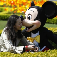 A woman meets Mickey Mouse at Tokyo Disneyland.  | REUTERS