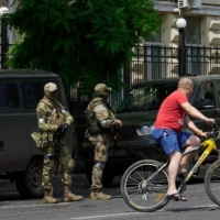A man rides a bicycle as members of Wagner Group stand guard in the city of Rostov-on-Don, Russia, on Saturday. | AFP-JIJI