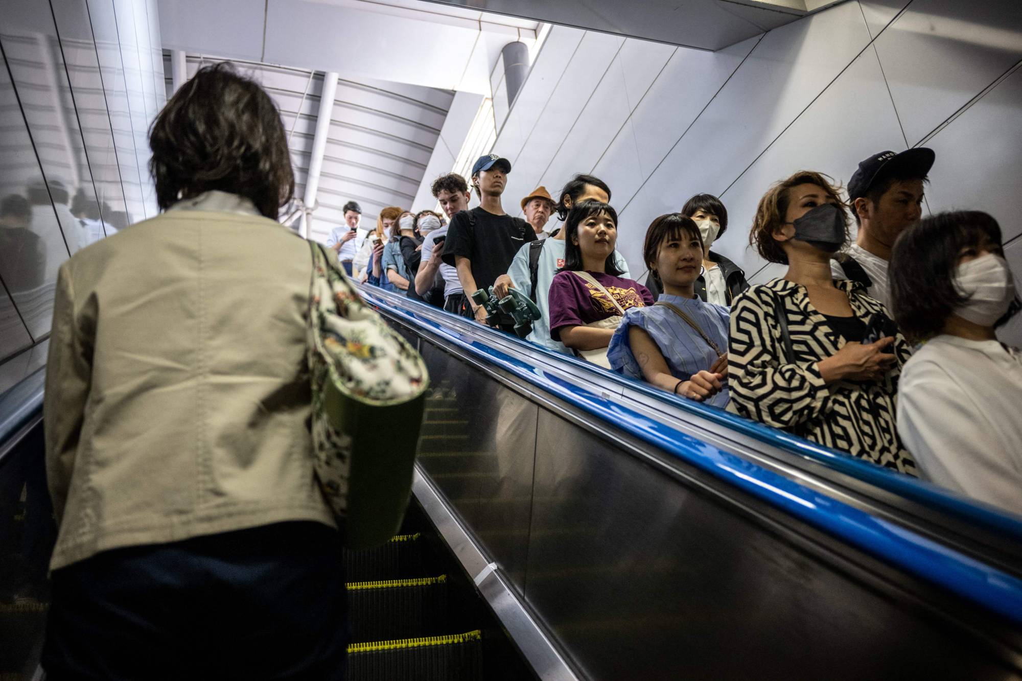 People ride on an escalator at Shinjuku Station in Tokyo on June 1. | AFP-JIJI