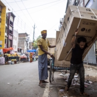 Laborers carry a refrigerator in Ballia. Heat waves hurt the poor disproportionately more as many work outside and don’t have access to well-ventilated housing or air conditioning.  | BLOOMBERG