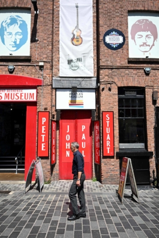 A pedestrian walks past pictures of two of the Beatles on Mathew Street in Liverpool. | AFP-JIJI