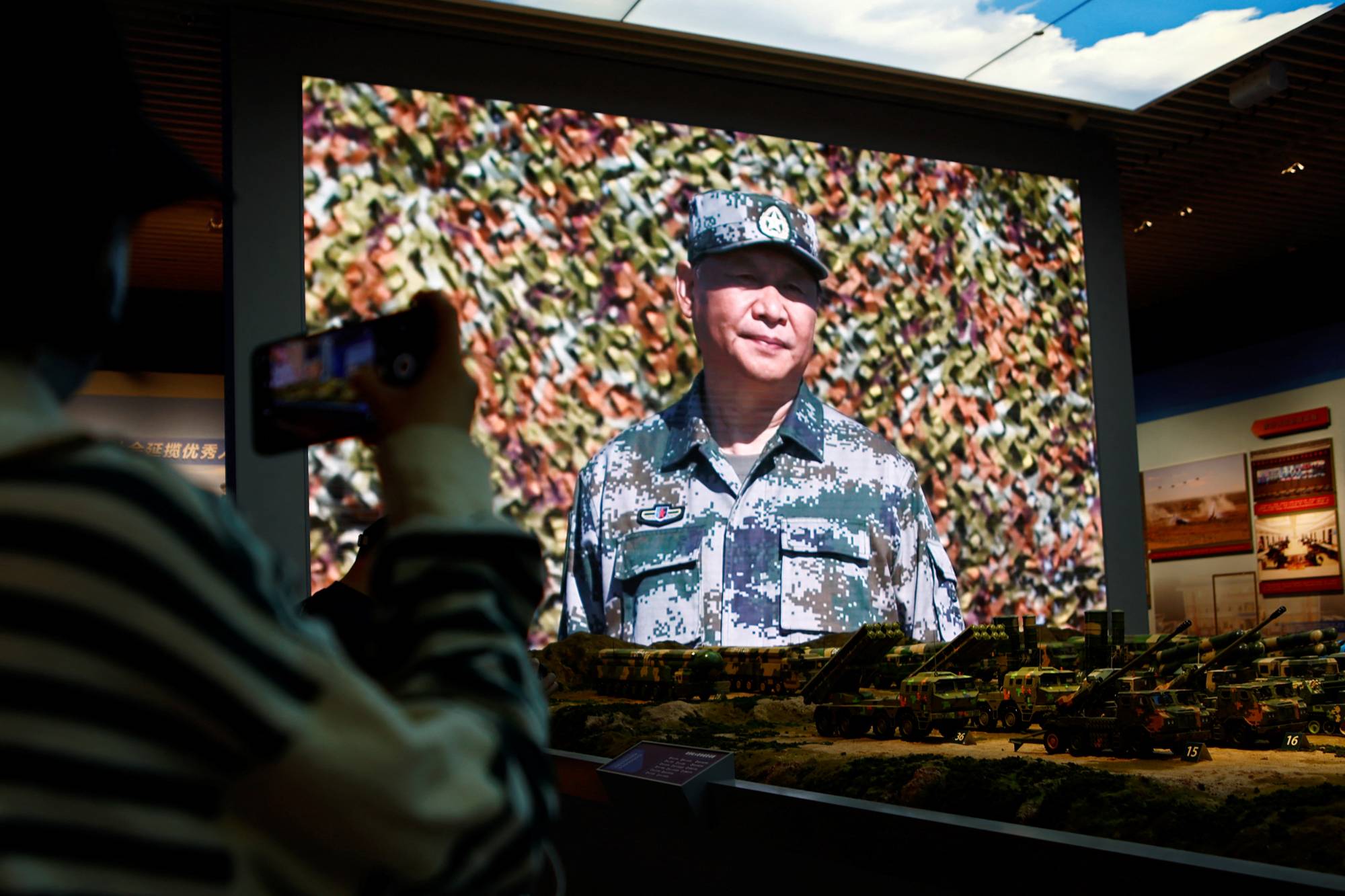 A visitor takes pictures near models of military equipment and a giant screen displaying Chinese leader Xi Jinping, in an exhibition at the Military Museum of the Chinese People's Revolution in Beijing last October. | REUTERS