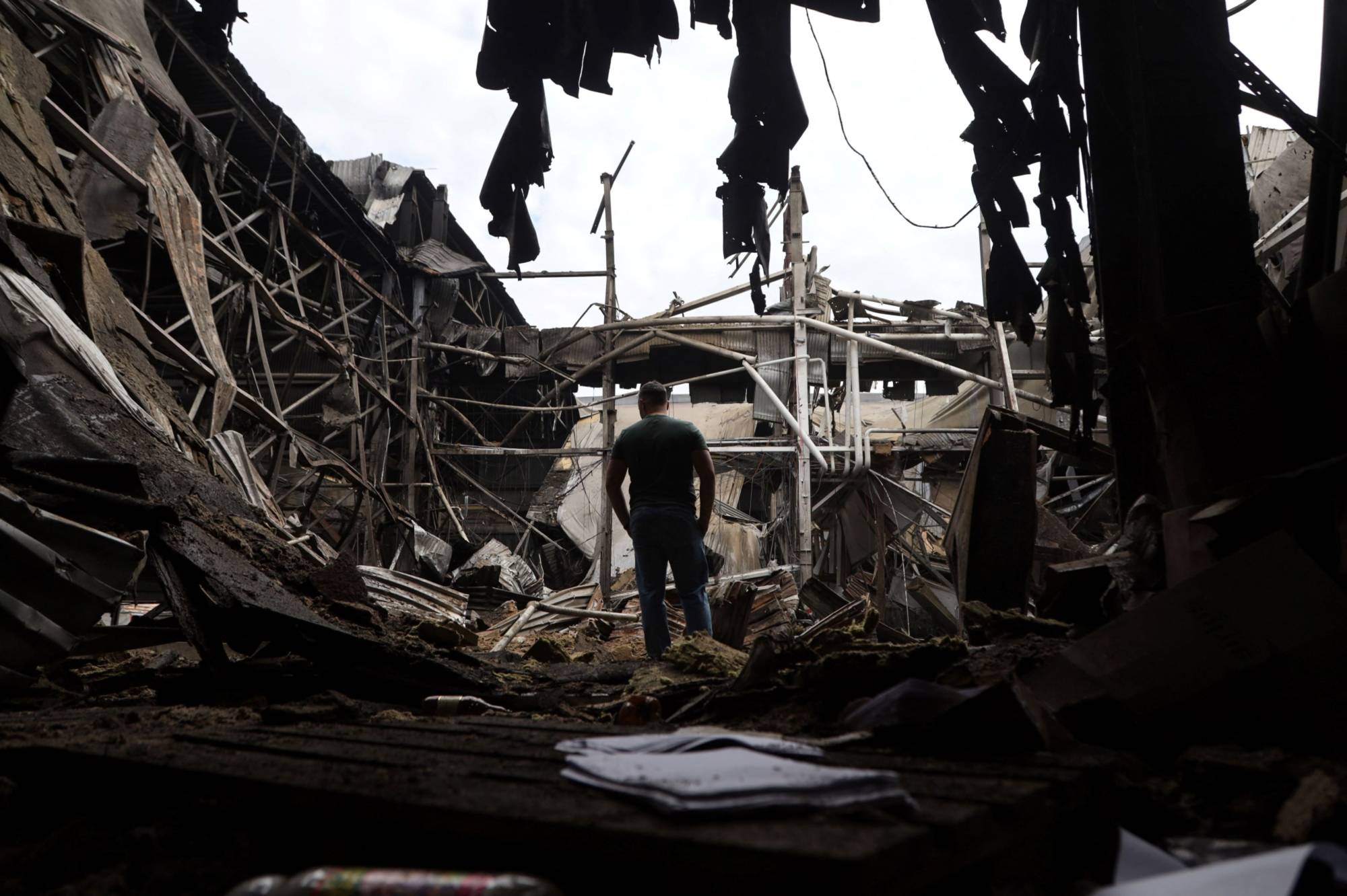 A man walks among debris in a damaged warehouse after a strike in Odesa, Ukraine, on June 14.  | GETTY IMAGES / AFP-JIJI