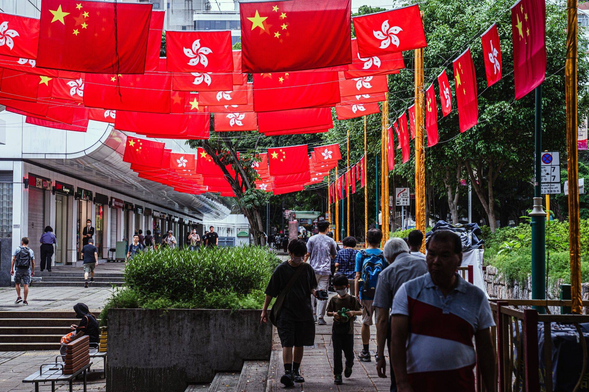 Pedestrians in Hong Kong under the flags of China and Hong Kong Special Administrative Region marking the 26th anniversary of Hong Kong's return to Chinese rule on Thursday | BLOOMBERG