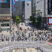 Pedestrians cross an intersection in the Shibuya district of Tokyo, in June. | BLOOMBERG