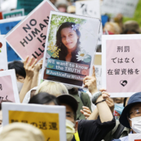 People opposing the revision of Japan\'s immigration control and refugee recognition law march in Tokyo on May 16, 2021. Many held up photos of Ratnayake Liyanage Wishma Sandamali, a Sri Lankan woman who died in March while being held at the Nagoya Regional Immigration Services Bureau in central Japan. | KYODO