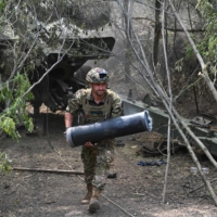 A Ukrainian soldier carrying a propellant charge for artillery takes part in fighting near Avdiivka, in the Donetsk region of Ukraine, on June 23.  |  AFP-JIJI