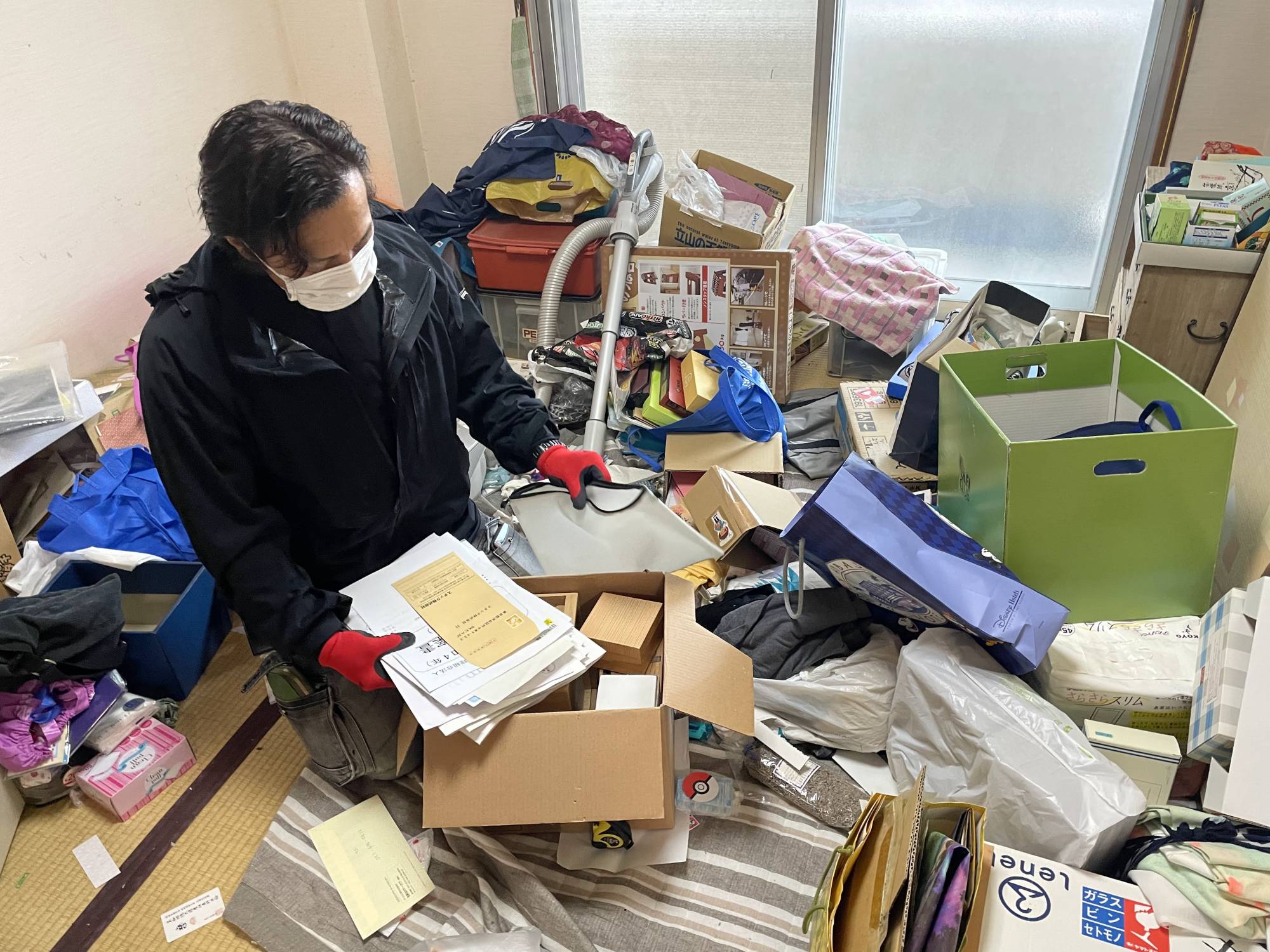 Tsuyoshi Sakota, the chairman of Bxia, sorts out a pile of documents left behind by the late owner of an apartment. | ALEX K.T. MARTIN