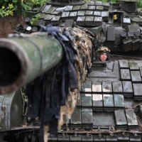 A Ukrainian serviceman sits on a T-72 tank at a position in the country\'s Donetsk region on Sunday. | AFP-JIJI