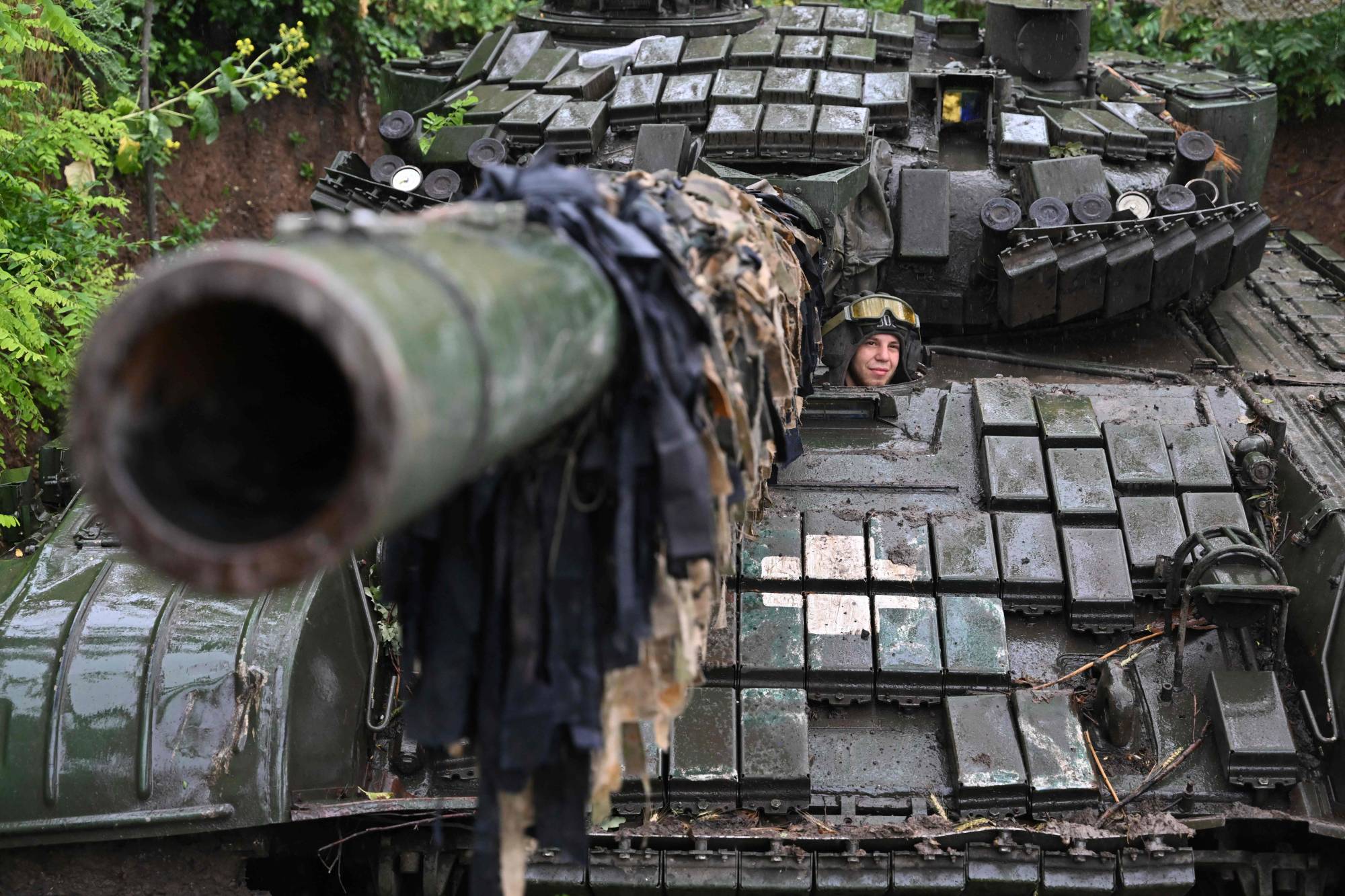 A Ukrainian serviceman sits on a T-72 tank at a position in the country's Donetsk region on Sunday. | AFP-JIJI