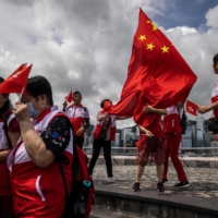 People wave the flags of Hong Kong and China on the Tsim Sha Tsui water front in Hong Kong on Saturday.  | AFP-JIJI