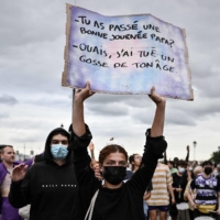 A protester holds a placard reading, \"Did you have a good day Dad? -Yeah, I killed a kid your age,\" in Bordeaux, southwestern France, on Friday. | AFP-JIJI
