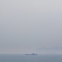 A Chinese naval ship can be seen in the distance near Dongju Island, Taiwan, on April 10. | LAM YIK FEI / THE NEW YORK TIMES