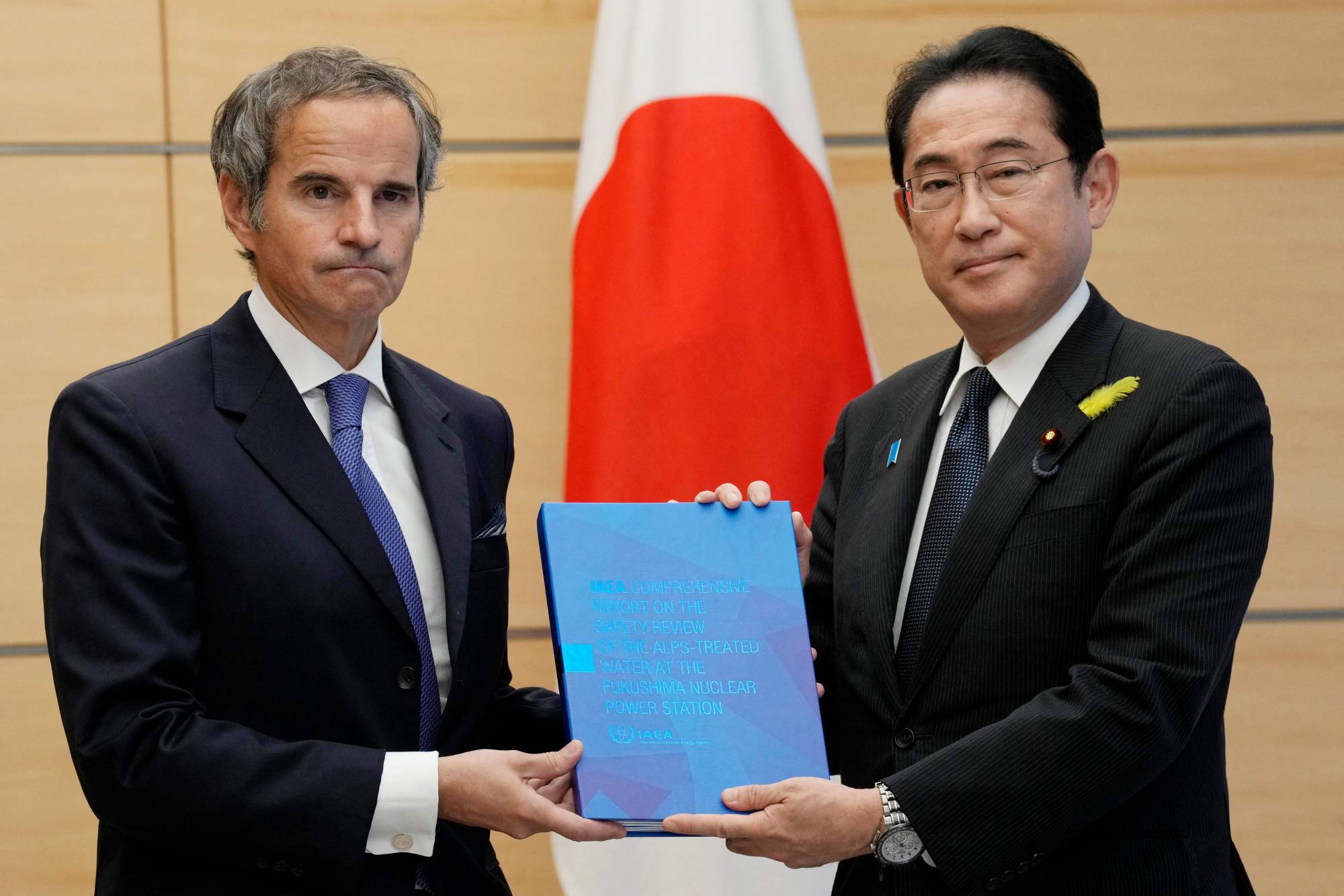Rafael Grossi, director general of the International Atomic Energy Agency, presents Prime Minister Fumio Kishida with the IAEA's comprehensive report on the plan to release treated water from the Fukushima No. 1 nuclear plant, at the Prime Minister's Office in Tokyo on Tuesday. | POOL / VIA AFP-JIJI