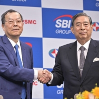 Frank Huang (left), chairman of Powerchip Semiconductor Manufacturing Corp., shakes hands with SBI President Yoshitaka Kitao at a news conference in Tokyo on Wednesday. | KYODO