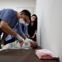 Song treats a baby as the child\'s mother, Jung Seung-yeon, 38, looks on. | REUTERS