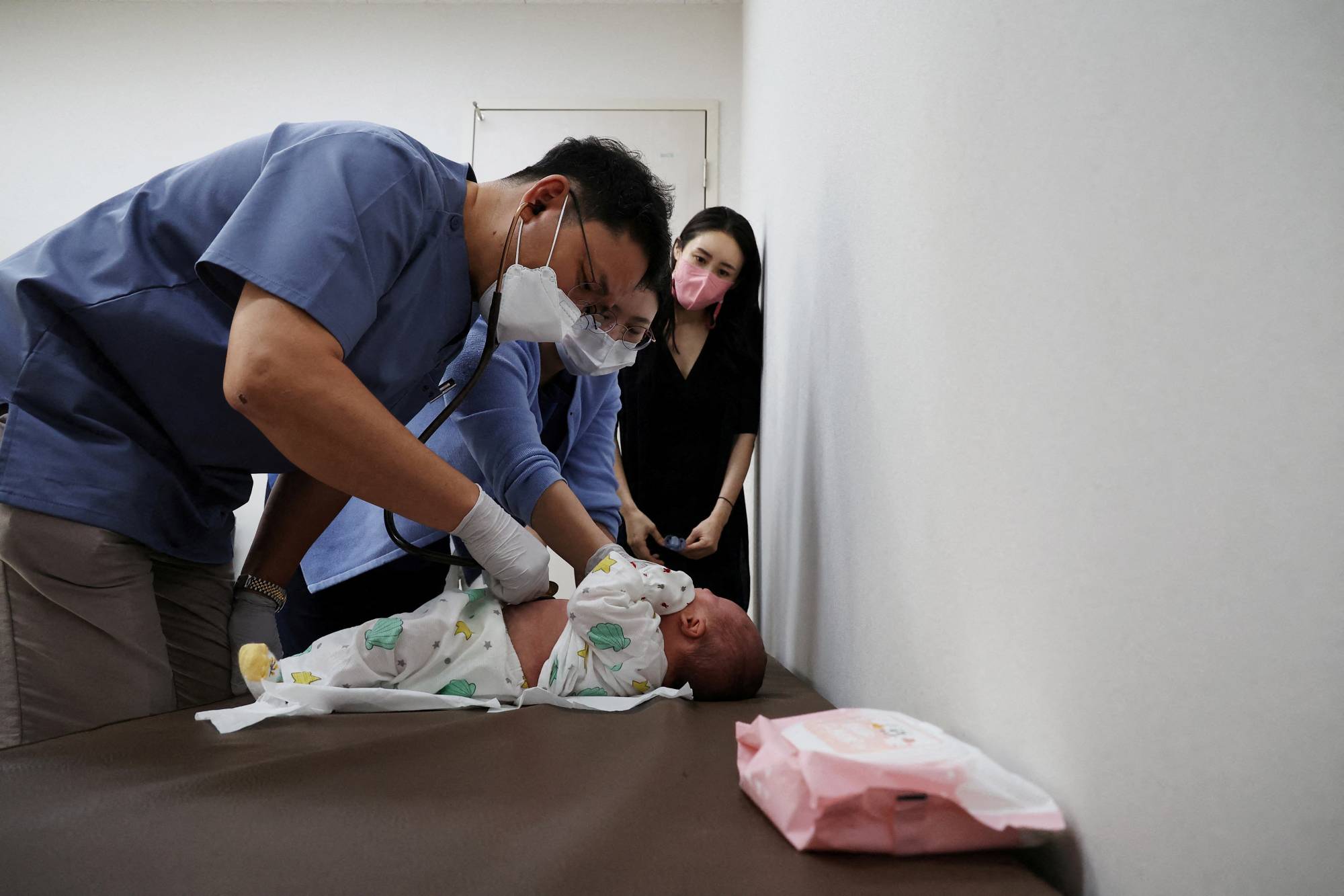 Song treats a baby as the child's mother, Jung Seung-yeon, 38, looks on. | REUTERS