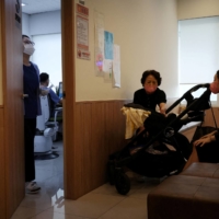 Jung Seung-yeon (R), 38, waits with her son at a pediatric clinic in Seoul. | REUTERS