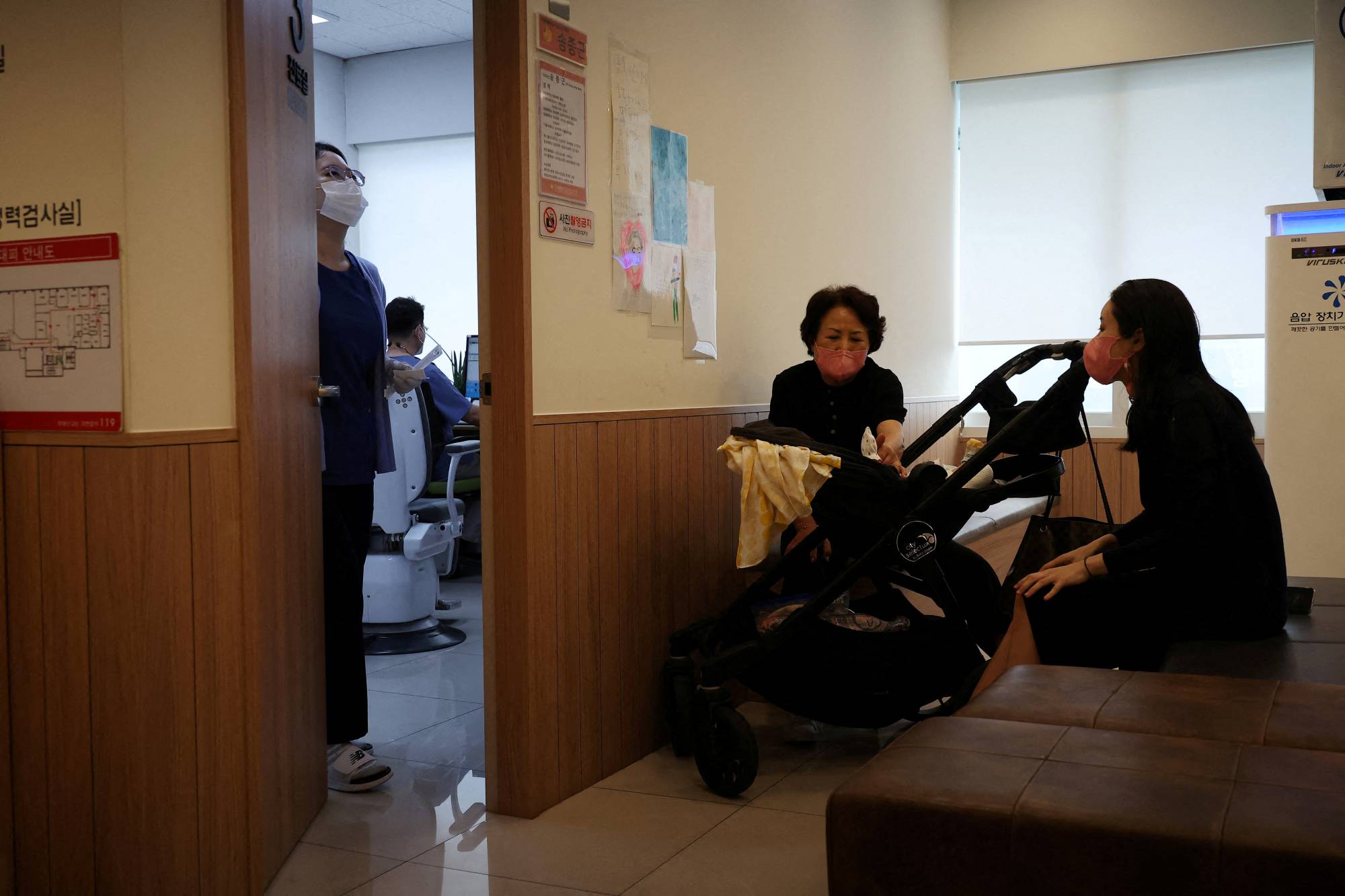 Jung Seung-yeon (R), 38, waits with her son at a pediatric clinic in Seoul. | REUTERS