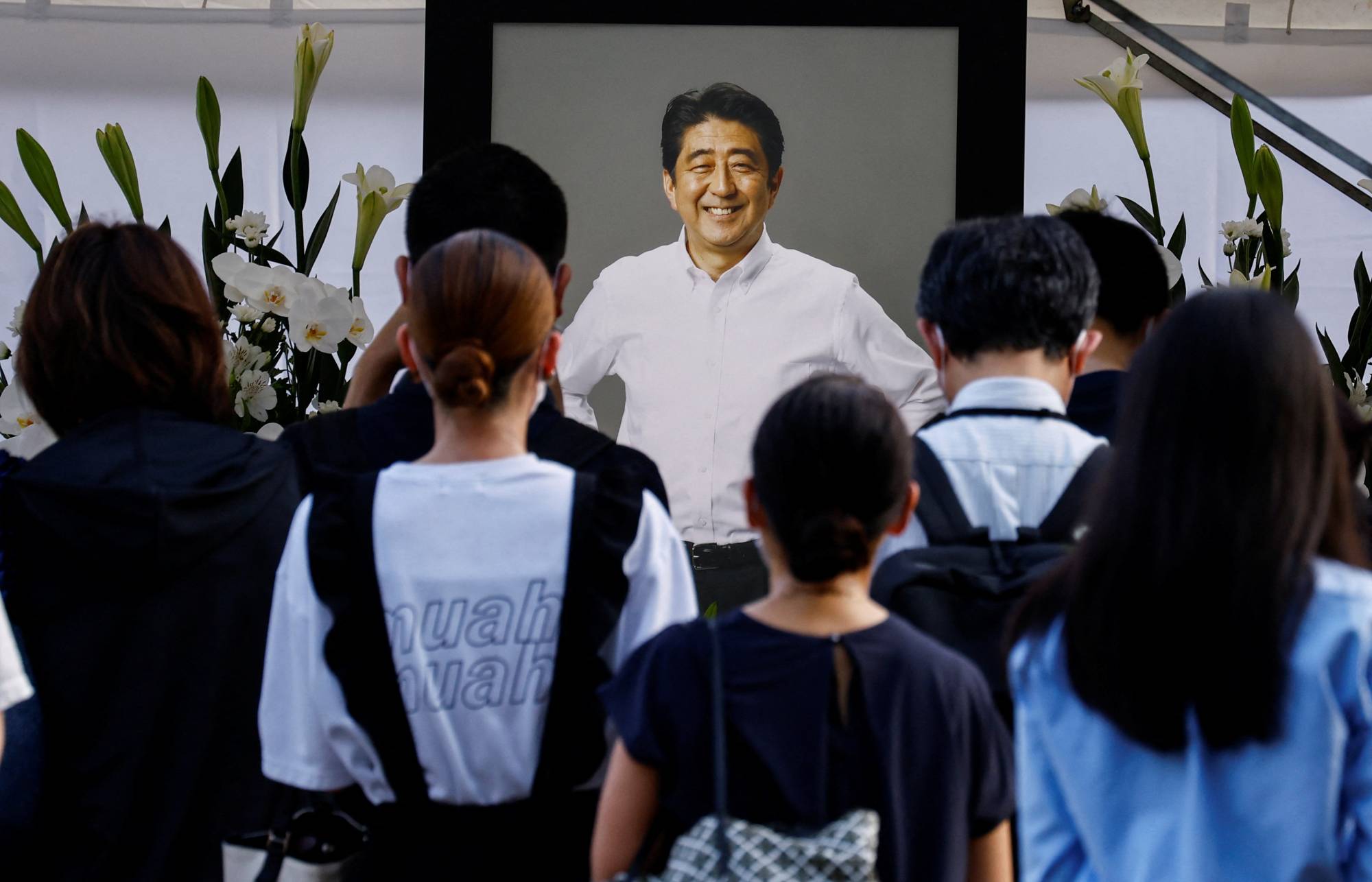 People lay flowers at Zojoji temple, the site of a vigil and the funeral for late former Prime Minister Shinzo Abe, who was shot while campaigning for a parliamentary election, in Tokyo in July 2022. | REUTERS