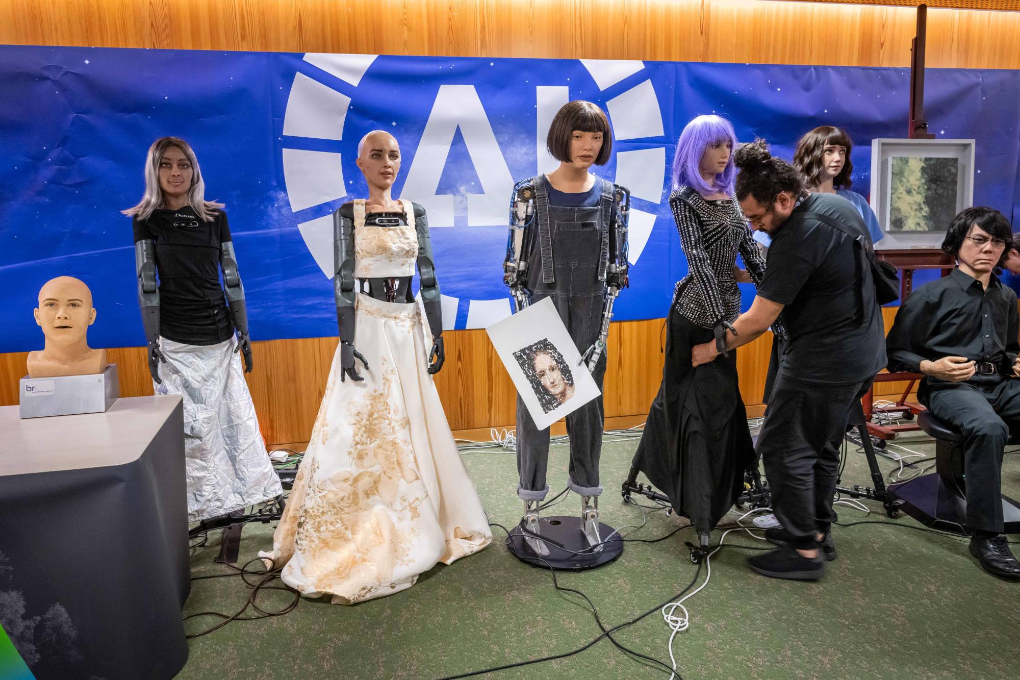 The head of AI robot Ameca (from left), CEO female robot Mika, AI robot Sophia, 'Ultra-realistic artist' robot Ai-Da,' AI robot Desdemona, health care assistant robot Grace and teleoperated android Geminoid HI-2 are showcased during what was presented as the world's first news conference with a panel of AI-enabled humanoid social robots at the AI for Good Global Summit in Geneva on Friday. 