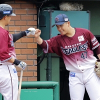 Hideto Asamura (left) is greeted in the dugout by Eagles pitcher Masaru Fujii after hitting a three-run home run in the third inning against the Hawks at Rakuten Mobile Park Miyagi on Sunday. | KYODO