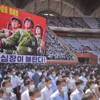 North Koreans attend a mass rally to mark the \"day of struggle against U.S. imperialism\" on June 25, at the May Day Stadium in Pyongyang. The banner reads: \"Tens of millions of people pledge to defy death for defending country!\" | AFP-JIJI