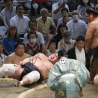 Nishikigi (right) throws down yokozuna Terunofuji to win their bout on the second day of the Nagoya Grand Sumo Tournament on Monday. | KYODO