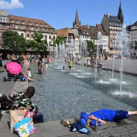 People cool off in water fountains in Strasbourg, France, amid a heat wave on Tuesday. | AFP-JIJI
