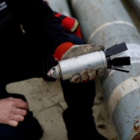 A Ukrainian military serviceman holds a defused cluster bomb from an MSLR missile in the region of Kharkiv, Ukraine, in October. | REUTERS