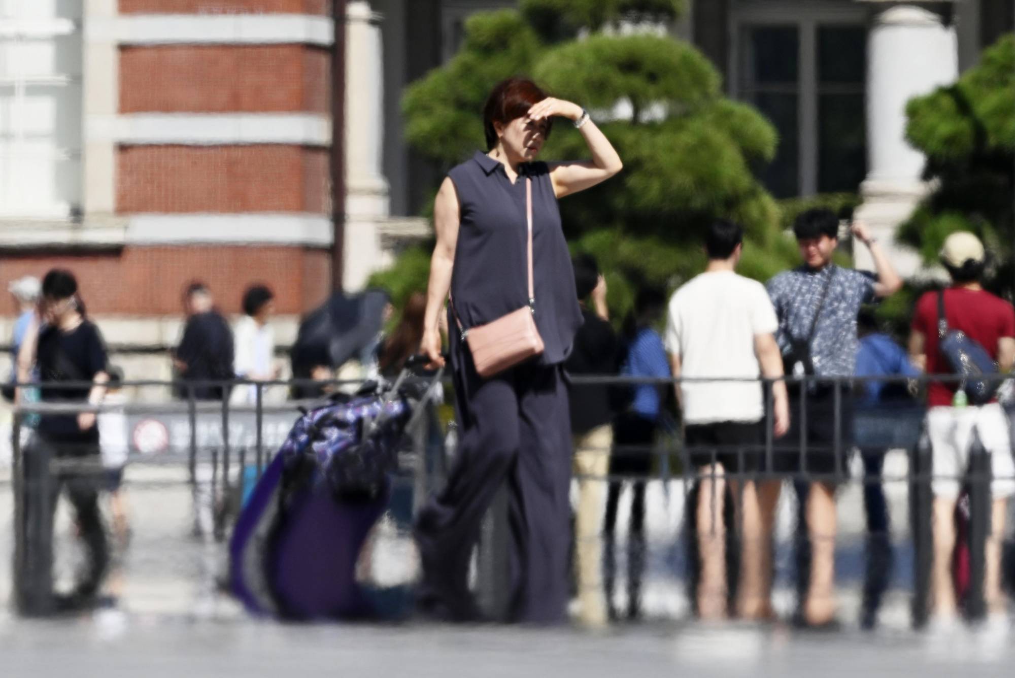 People pass by JR Tokyo Station on Monday afternoon. In central Tokyo on Tuesday, the temperature rose at a fast pace from the morning, rising above 30 degrees Celsius just after 6 a.m. | KYODO