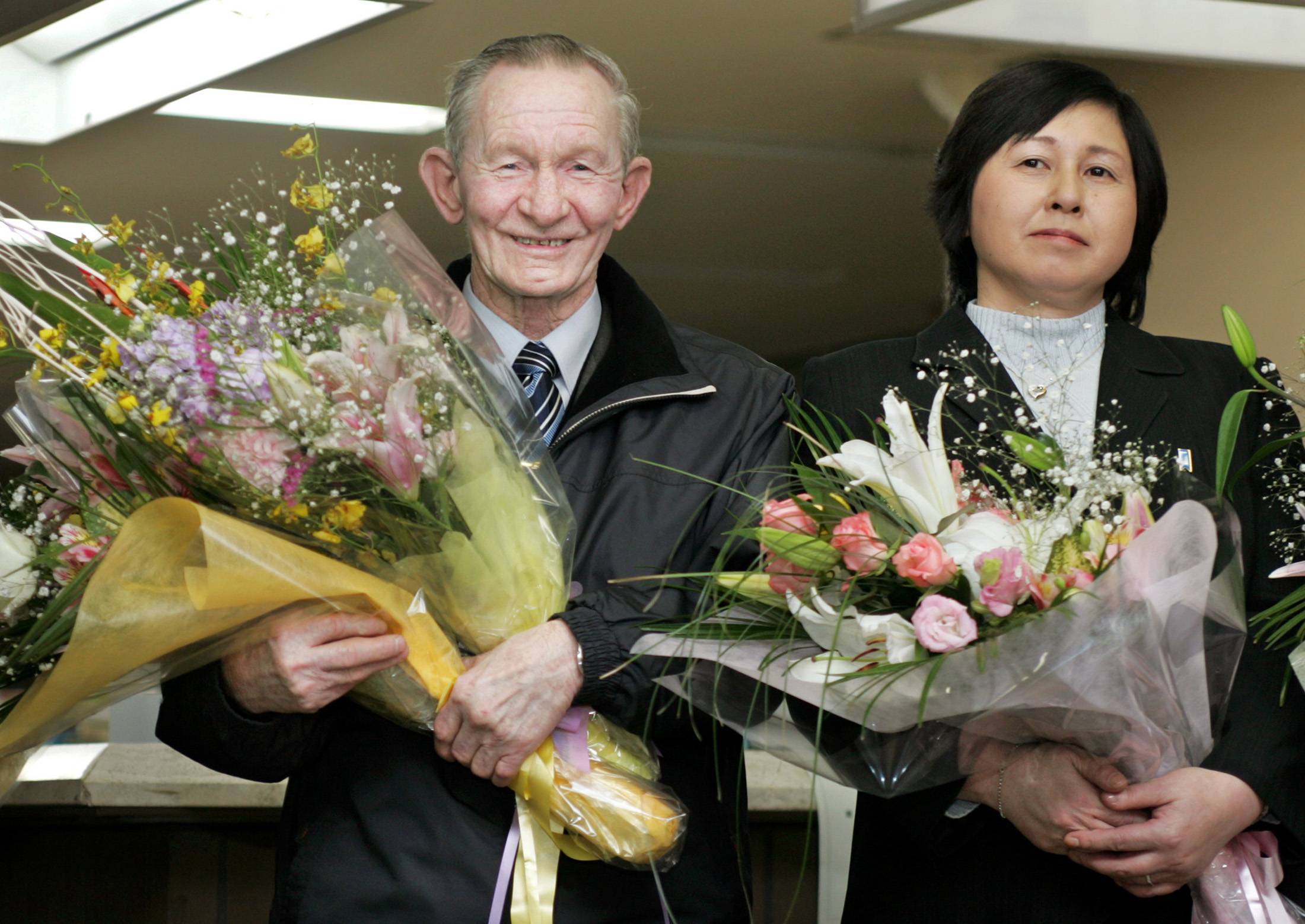 Former U.S. Army Sgt. Charles Robert Jenkins, who deserted to North Korea in 1965 and his Japanese wife, Hitomi Soga, who was abducted by North Korean agents in 1978, smile as they receive flower bouquets upon arrival at a town hall in Soga's hometown of Sado, Niigata Prefecture, in December 2004.  | REUTERS