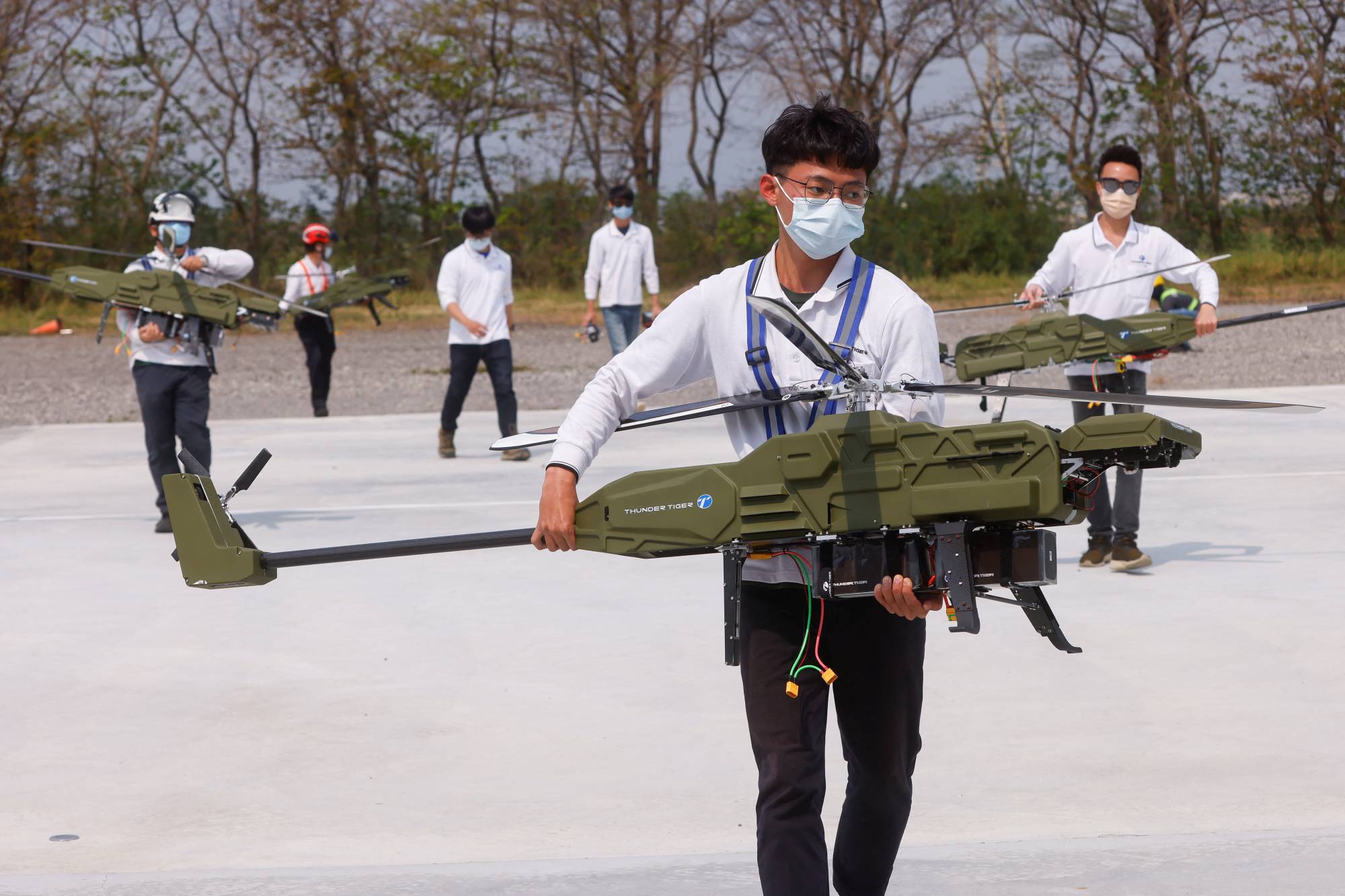 Staff members carry Thunder Tiger Group's unmanned aerial vehicles during a demonstration at a government-led Asia UAV AI Innovation Application R&D Center in Chiayi, Taiwan, on March 30. | REUTERS